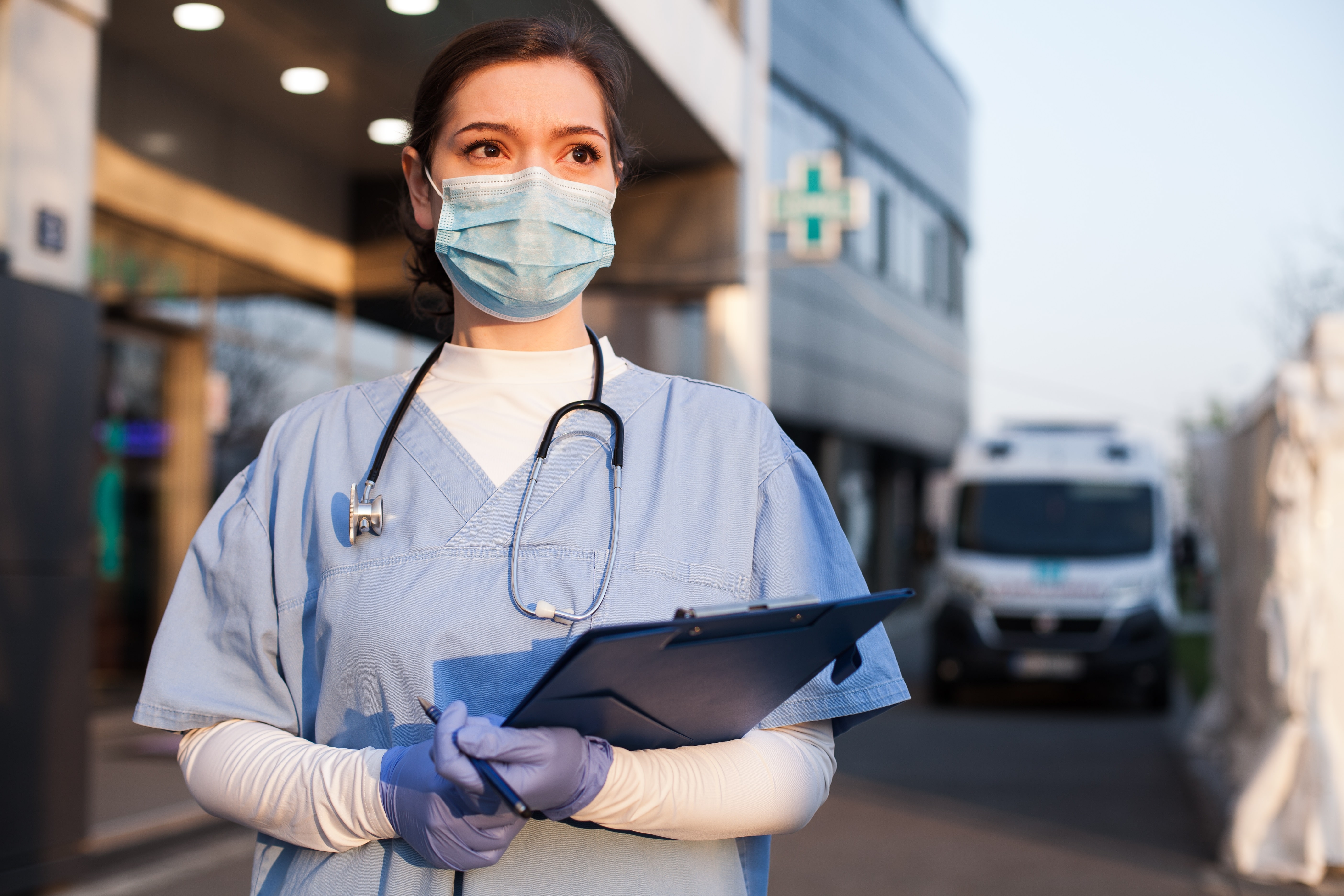 Masked healthcare professional near an ambulance
