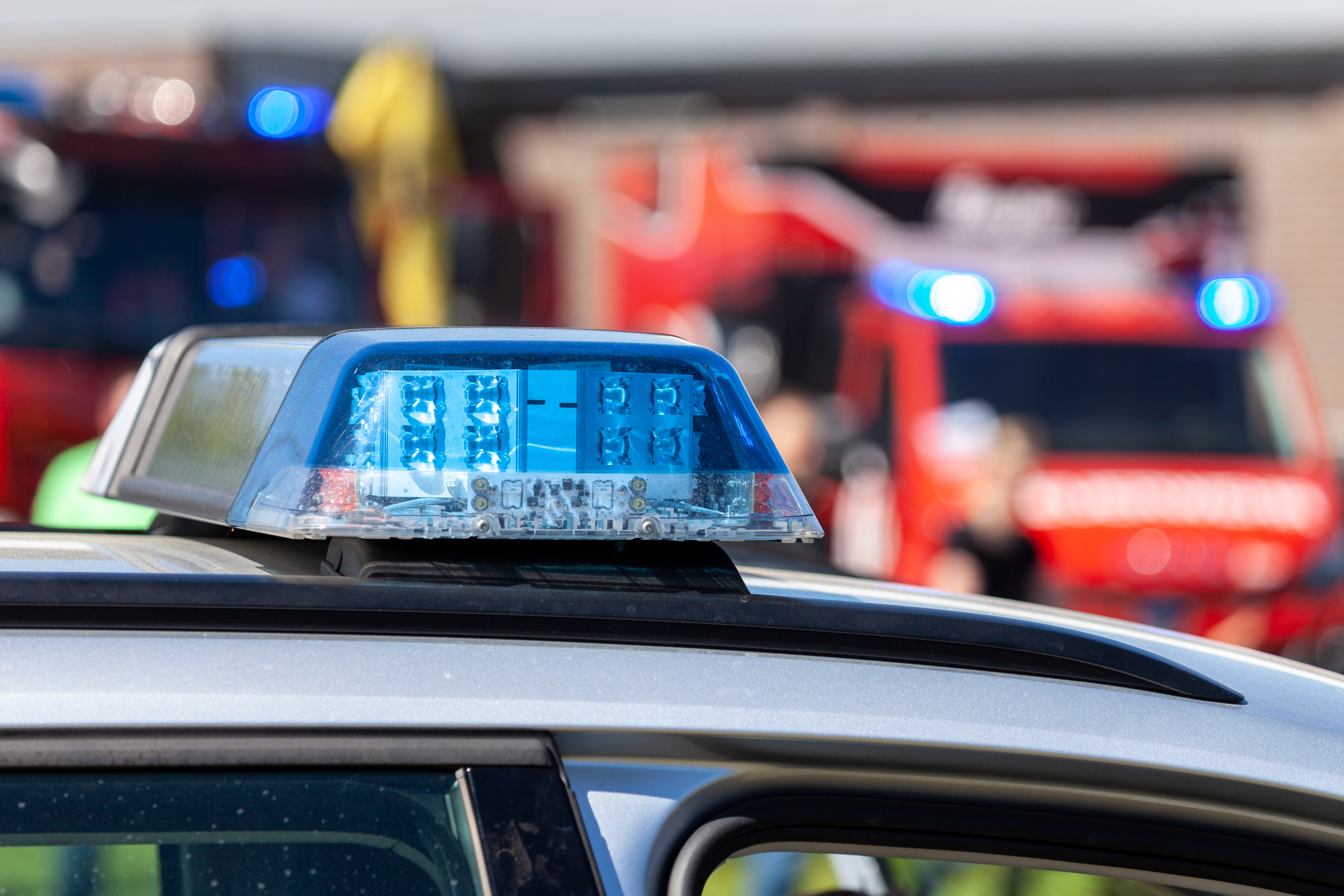 Blue light bar on a police car and a nearby blurred ambulance