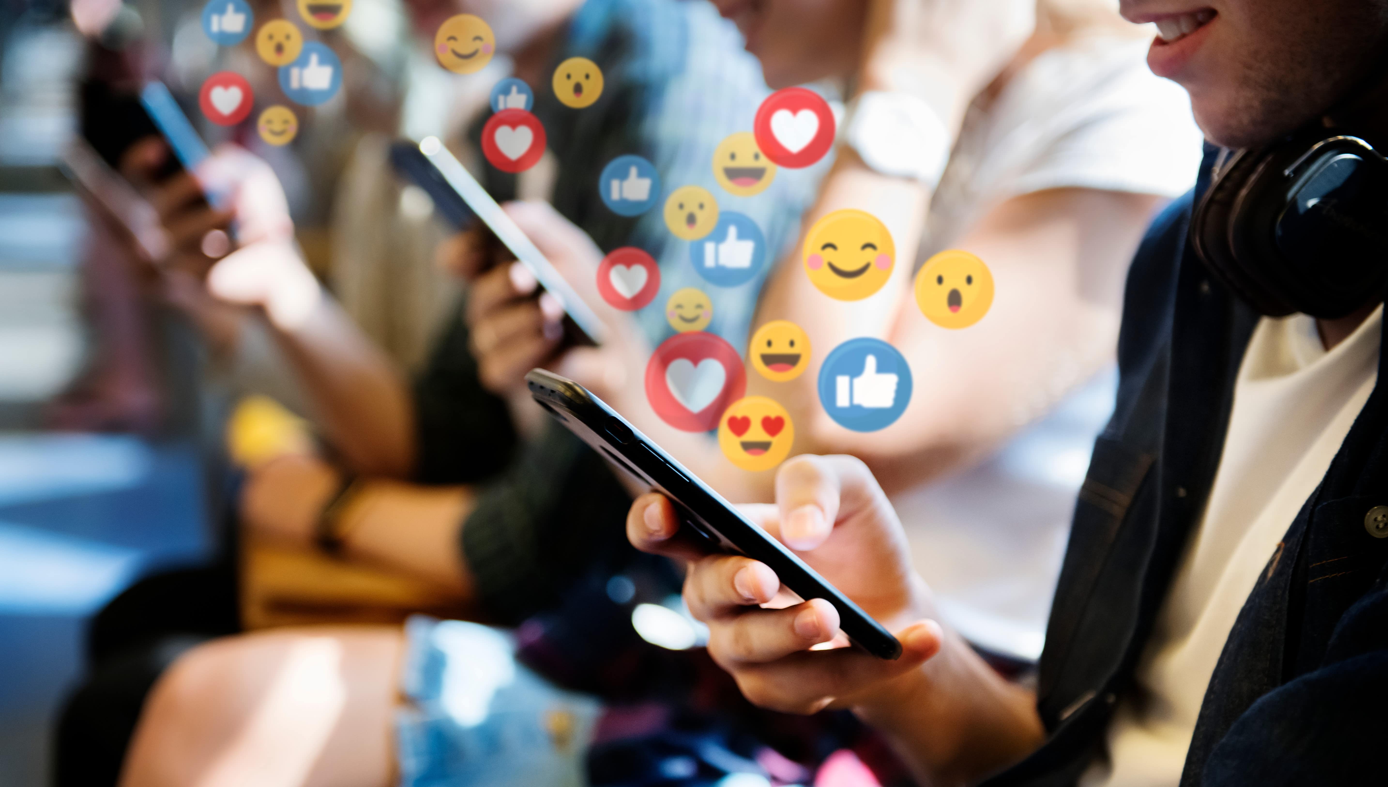 People using mobile phones with floating social media symbols