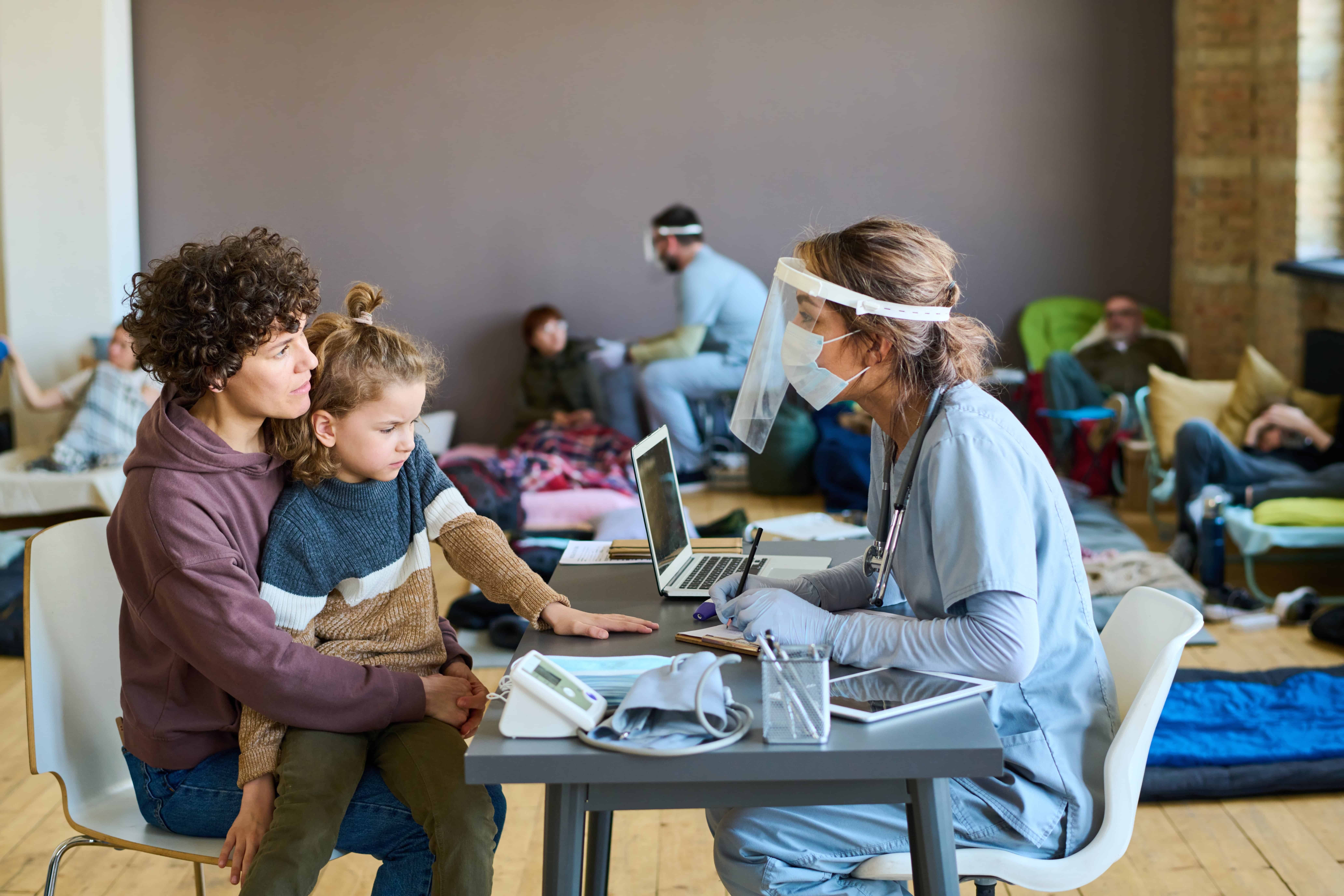 Medical professional speaking with a homeless woman and child