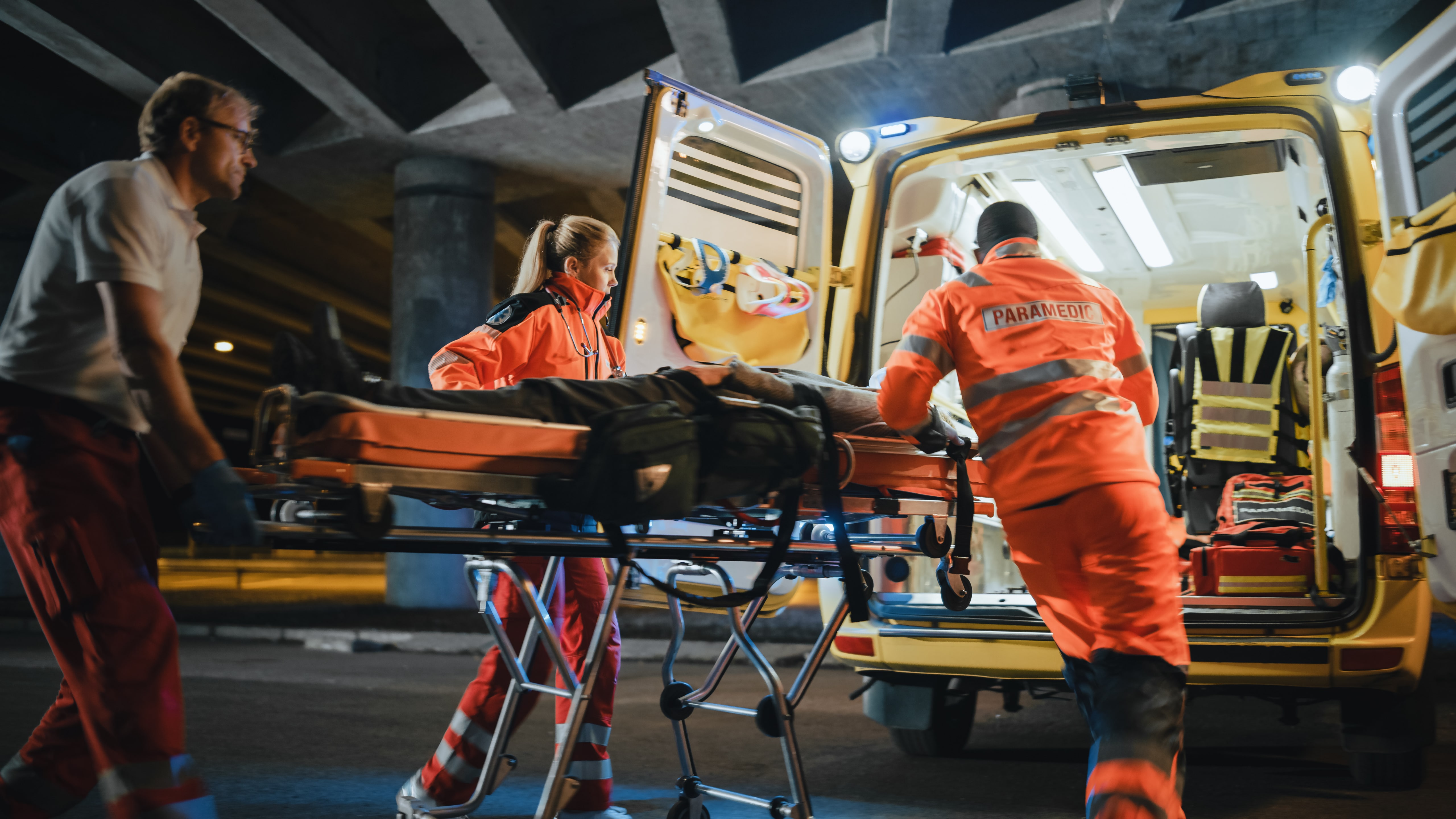 Paramedics lifting a man into an ambulance