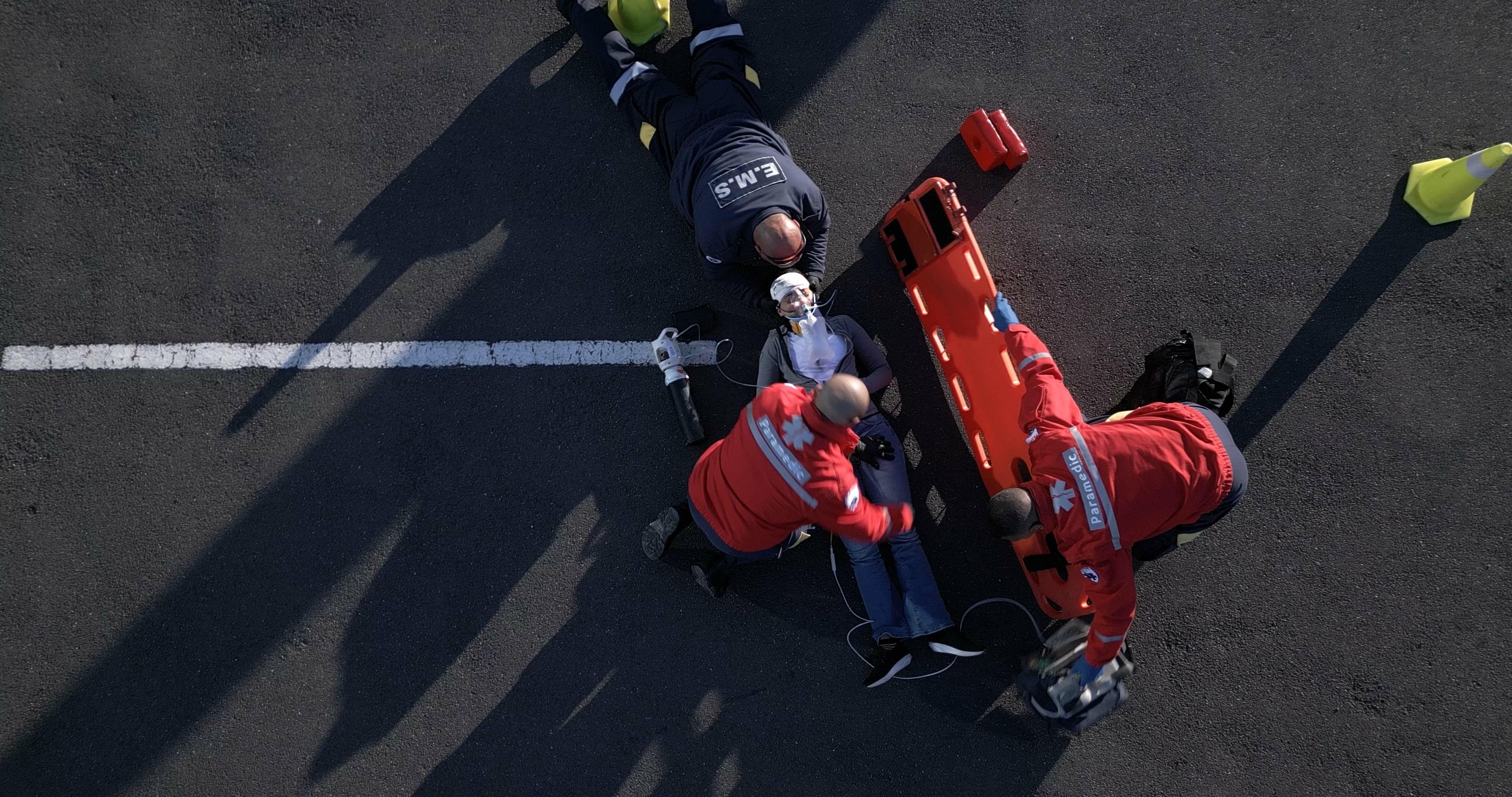 EMS professionals treating a car crash victim on the road