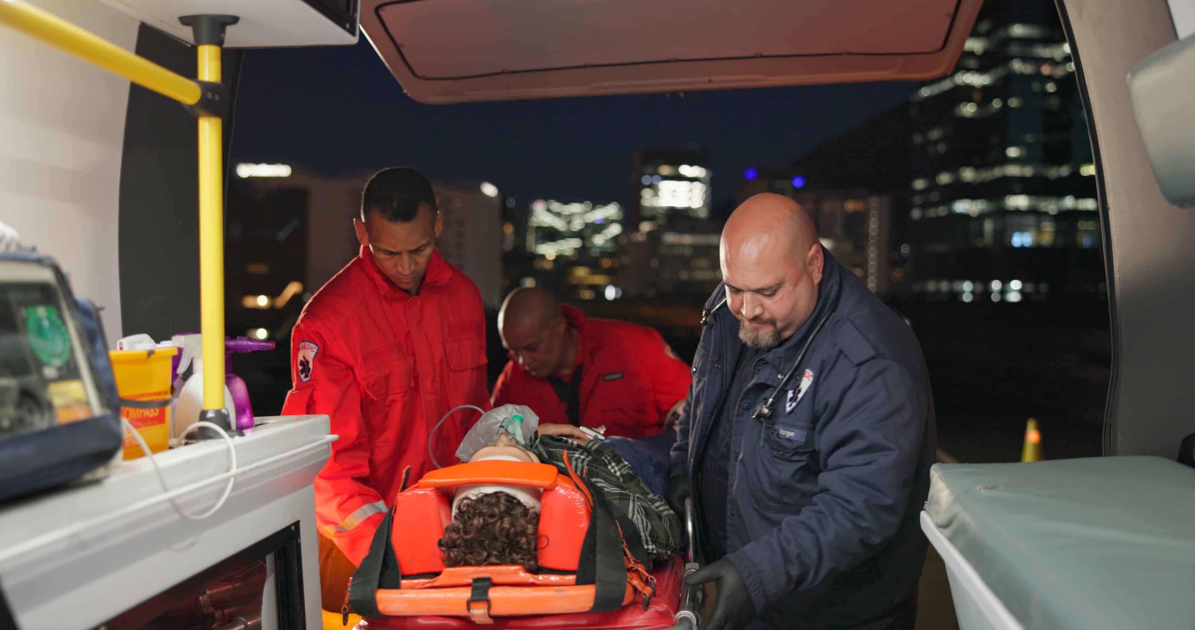 EMS team loading a person on a stretcher into an ambulance