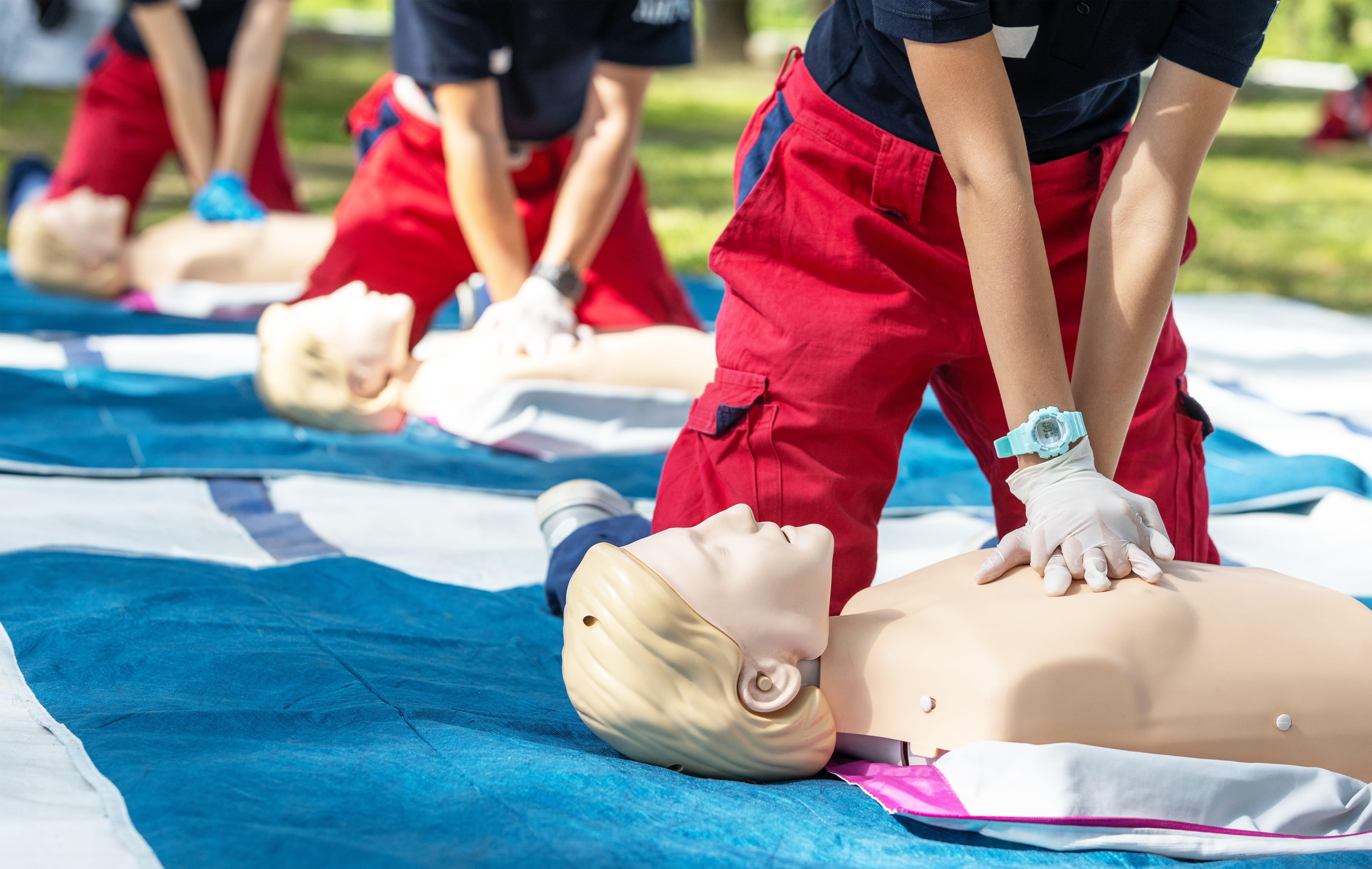 EMS professionals performing CPR outside on mannequins