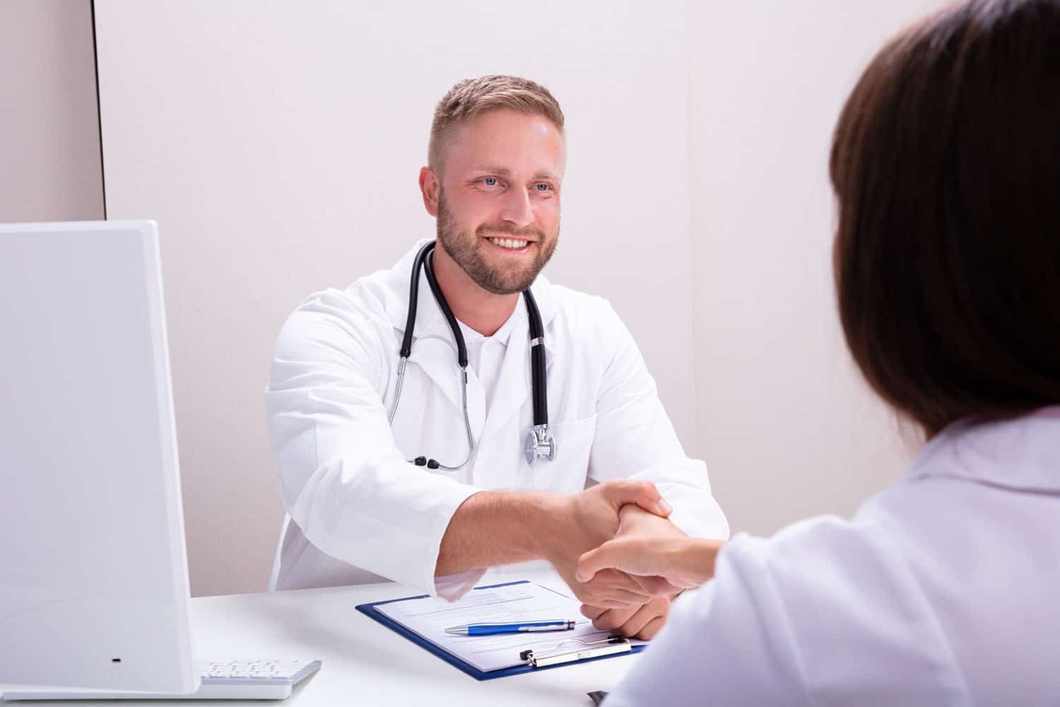 Medical professionals shaking hands over a desk