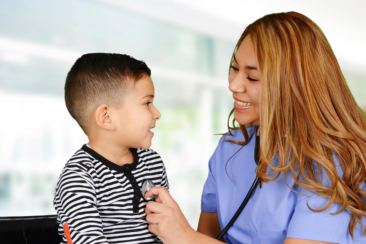 Hispanic nurse listening to a child's heartbeat